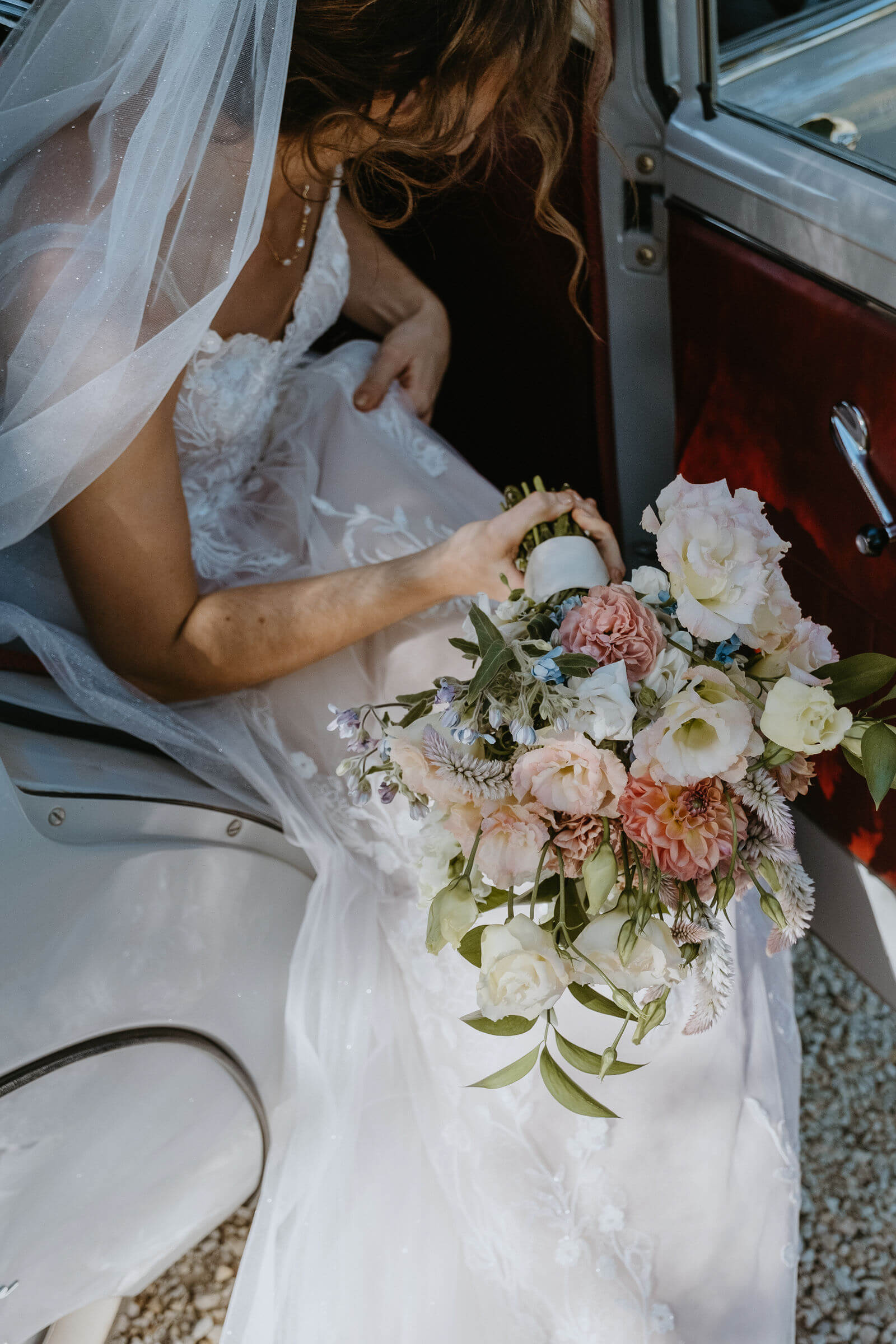 Bride holding bouquet stepping out of car