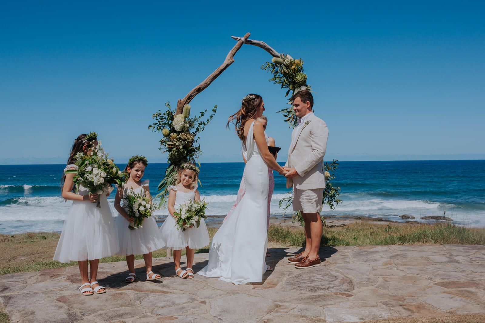 Bride, groom, and flowers girls under the arch.